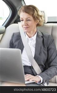 Confident mature businesswoman using laptop in car