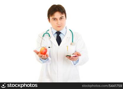 Confident medical doctor with tablets in one hand and apple in other isolated on white&#xA;