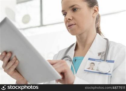 Confident mid adult doctor using digital tablet at clinic