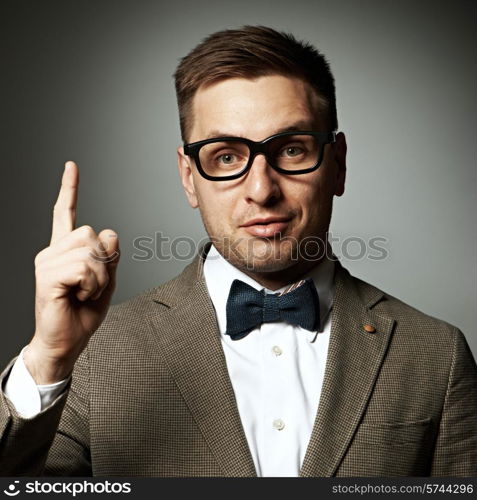 Confident nerd in eyeglasses and bow tie against grey background