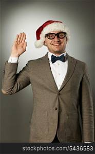 Confident nerd in Santa Claus hat and bow tie celebrates Christmas