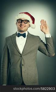 Confident nerd in Santa Claus hat and bow tie celebrates Christmas