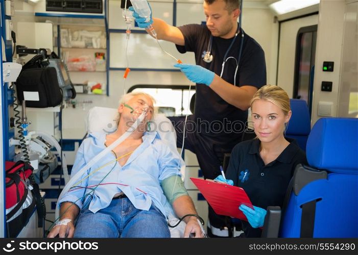 Confident paramedic treating injured elderly patient on stretcher in ambulance