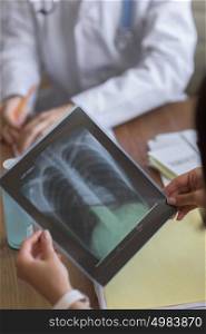 Confident practitioner consulting woman in hospital. Explaining results of chest x-ray scan