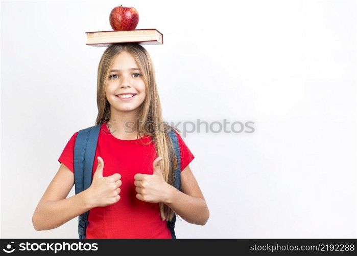 confident schoolgirl balancing book head