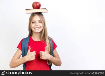 confident schoolgirl balancing book head
