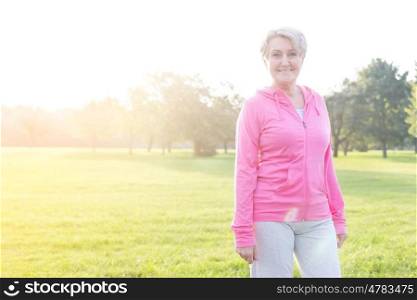 Confident senior athlete standing on grassy field in park