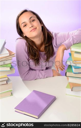 Confident student girl between stacks of books on purple background