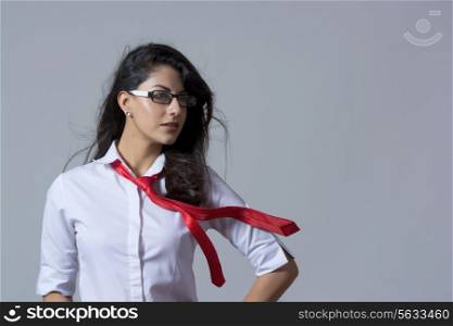 Confident stylish businesswoman with windswept tie against gray background