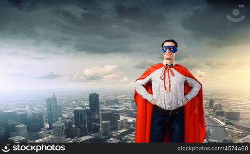 Confident superhero. Young man wearing superman mask and cape