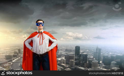 Confident superhero. Young man wearing superman mask and cape