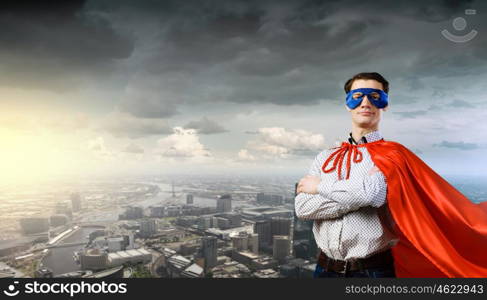 Confident superhero. Young man wearing superman mask and cape