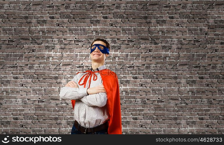 Confident superhero. Young man wearing superman mask and cape