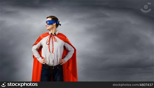 Confident superhero. Young man wearing superman mask and cape