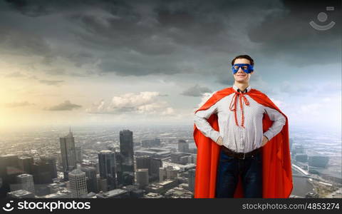 Confident superhero. Young man wearing superman mask and cape