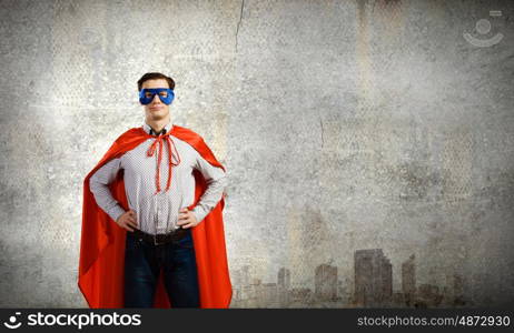 Confident superhero. Young man wearing superman mask and cape