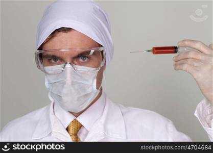 Confident surgeon holding a syringe against a white background