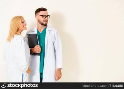 Confident surgical doctor holds document clipboard while standing with another doctor on white background. Medical service and healthcare people concept.. Confident doctor team on a white background.