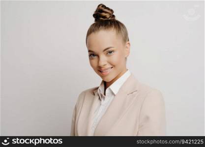 Confident woman manager in classic wear, charming smile, assertive look, standing near light background. Successful business people. 