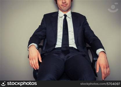 Confident young businessman is sitting in an office chair