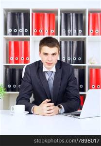 confident young businessman sitting at table in his office