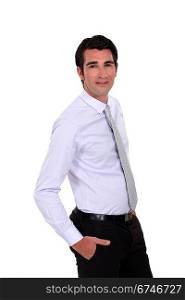 Confident young businessman stood with hands in his pockets