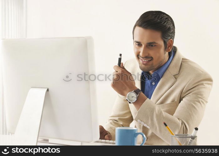 Confident young businessman using computer at office desk