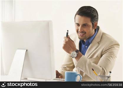 Confident young businessman using computer at office desk