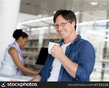 Confident young businessman with his collegue in the background
