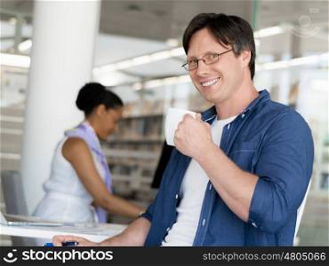 Confident young businessman with his collegue in the background