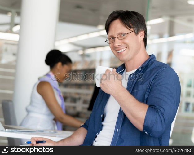 Confident young businessman with his collegue in the background