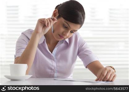 Confident young businesswoman busy reading document