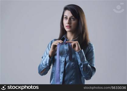 Confident young businesswoman getting dressed against gray background