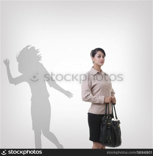 Confident young businesswoman standing in front of shadow dancing over gray background