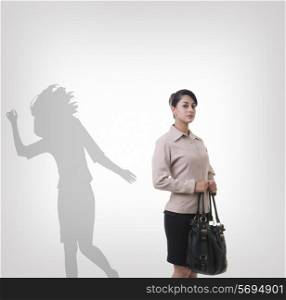 Confident young businesswoman standing in front of shadow dancing over gray background