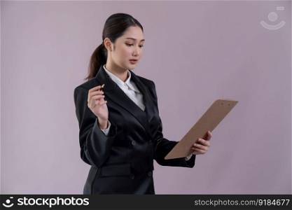 Confident young businesswoman stands on isolated background, holding clipboard and posing in formal black suit. Office lady or manager with smart and professional appearance. Enthusiastic. Confident young businesswoman stands on isolated background. Enthusiastic
