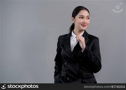 Confident young businesswoman stands on isolated background, posing in formal black suit. Office lady or manager with smart and professional appearance. Enthusiastic. Confident young businesswoman stands on isolated background. Enthusiastic