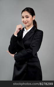 Confident young businesswoman stands on isolated background, posing in formal black suit. Office lady or manager with smart and professional appearance. Enthusiastic. Confident young businesswoman stands on isolated background. Enthusiastic