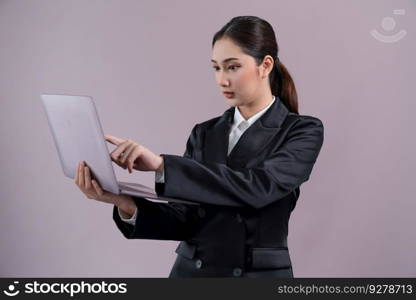 Confident young businesswoman stands on isolated background, working on laptop posing in formal black suit. Office lady or manager with smart and professional appearance. Enthusiastic. Businesswoman with laptop stands on isolated background. Enthusiastic