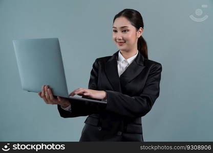 Confident young businesswoman stands on isolated background, working on laptop posing in formal black suit. Office lady or manager with smart and professional appearance. Enthusiastic. Businesswoman with laptop stands on isolated background. Enthusiastic