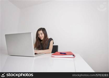 Confident young businesswoman using laptop at office desk
