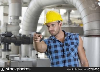 Confident young male worker pointing away in industry