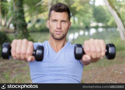 confident young man doing weights outdoors