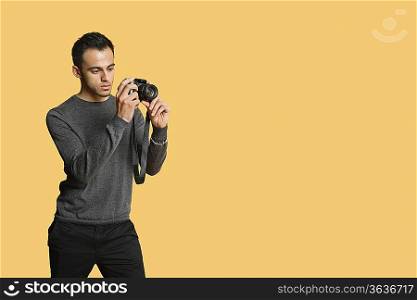 confident young man with digital camera over colored background