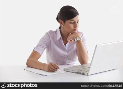 Confident young woman taking down notes from laptop