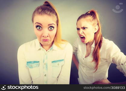 Conflict, bad relationships, friendship difficulties. Two young women having argument. Angry fury girl screaming at her friend or younger sister. Angry fury girl screaming at her friend or younger sister