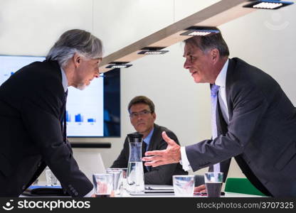 Conflict in office : Business executive arguing with his boss at meeting over latest sales figures with others watching