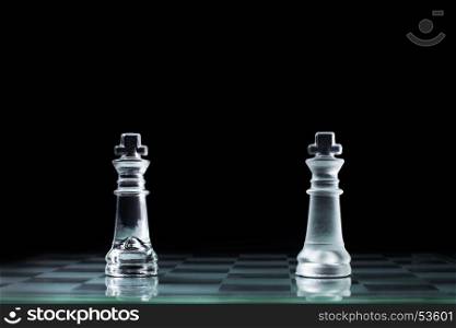 Confrontation - two wooden chess king standing against each other on a chessboard.