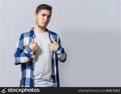 Confused caucasian young man pointing at himself. Confused person pointing at himself isolated. Confused latin guy pointing at himself isolated, Portrait of confused teenager pointing at himself