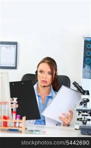 Confused doctor woman with headset looking on clipboard and notepad in hands&#xA;